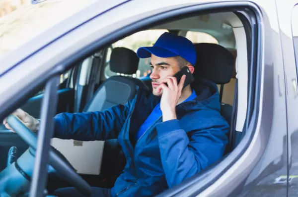 An field employee driving a car and communicating with team by using field service management app on mobile