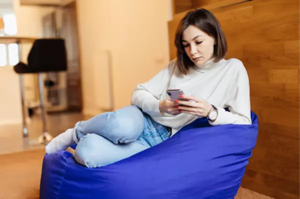 A girl seated on sofa and giving live reporting with the help of field service management app on mobile